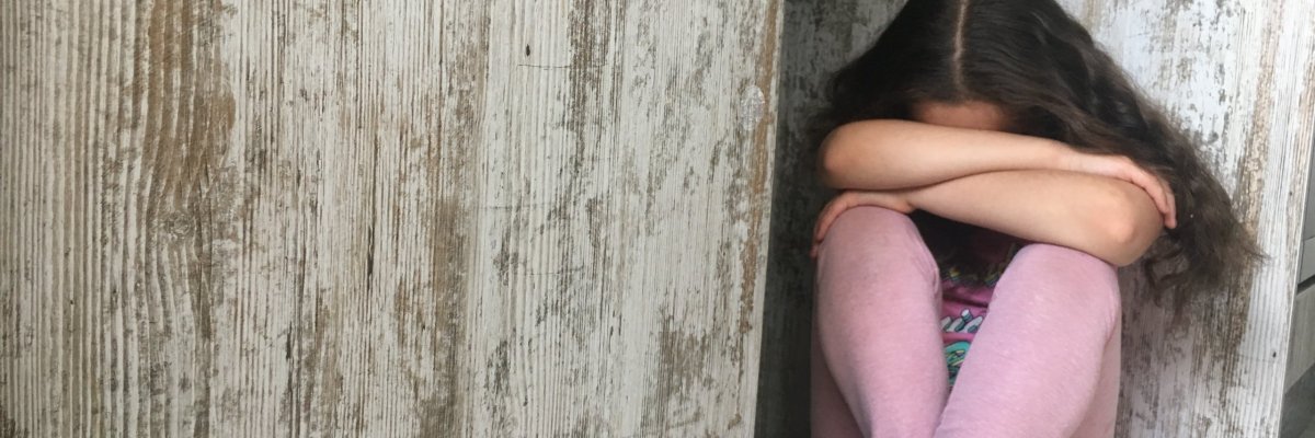 Niña de brazos cruzados Niña sentada en el suelo